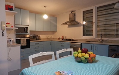 Muebles de cocina sin manilla postformados color celeste con cubierta de granito blanco, instalados en Vitacura